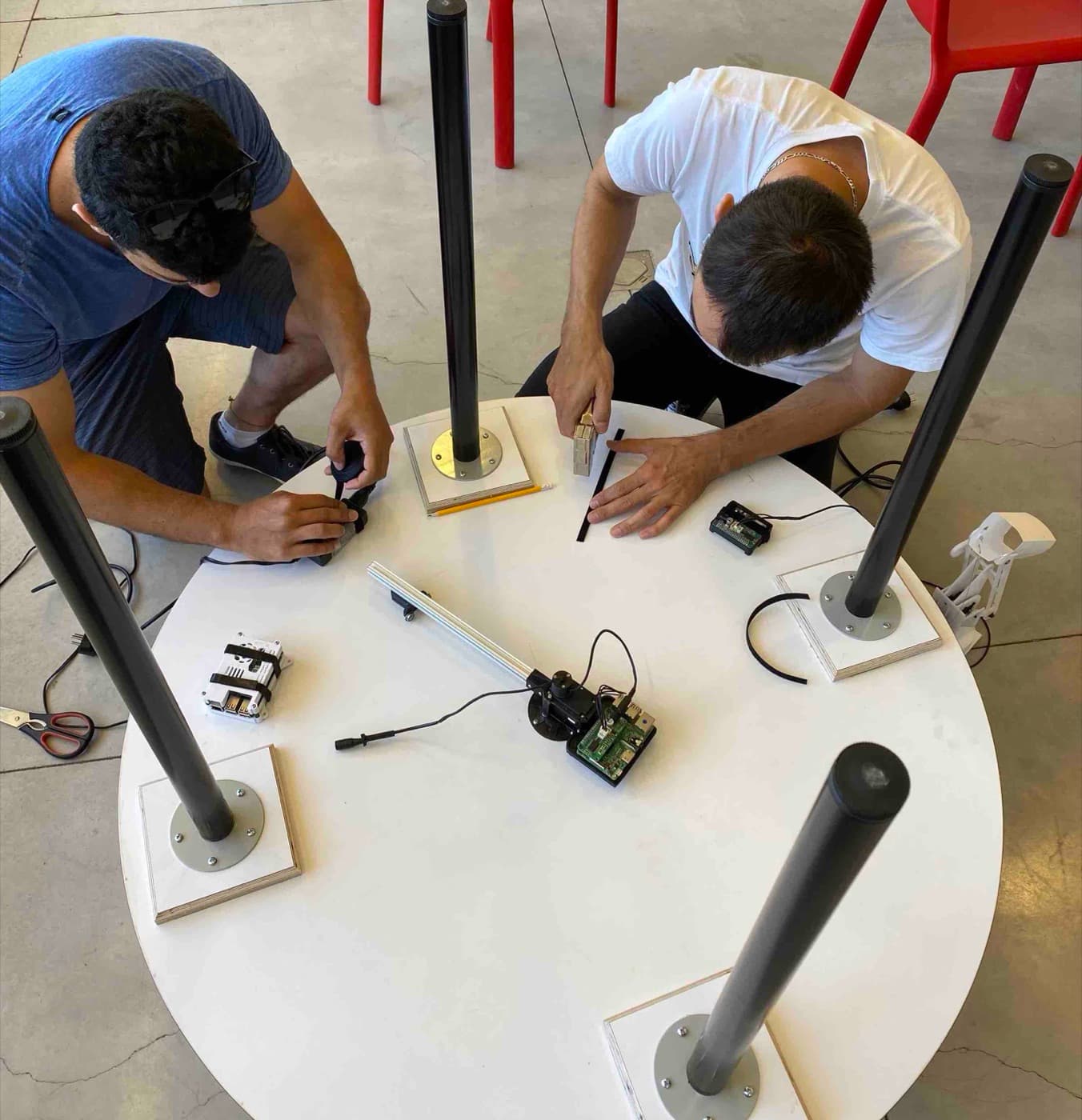 Two team members assembling the robots and the robotic arm on the round table.